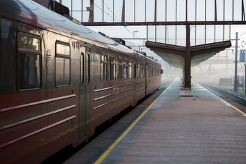 A horizontal shot of an empty Bergen train station, with a red train waiting to depart on a misty...