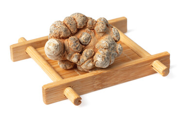 Dried herb, notoginseng roots in the bamboo plate, isolated on white background