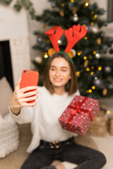Close up of young girl telephone to parents and show a red Christmas gift in focus