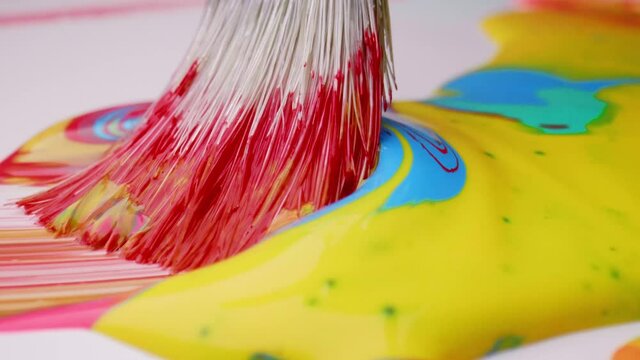 Fibers of brush mixing bright colors on paper surface