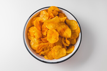Smoked paprika potato chips in bowl on white background. Fast food, junk food and unhealthy snacks concept. Top view, copy space