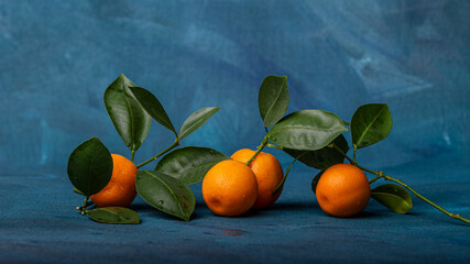 Ripe gorgeous tangerines with leaves on blue background.