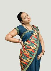 An Indian pregnant lady holding her right back and lower belly with one hand eyes closed feeling,...