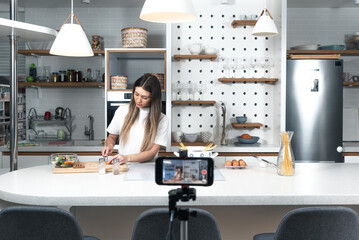 Young vlogger woman vlogging about cooking at her apartment domestic kitchen cook and making video...