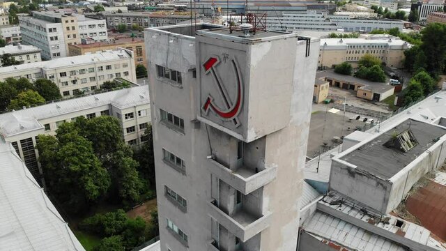 A building with a red hammer and sickle monument. USSR communism symbols Constructivism. St. Petersburg near the Narvskaya metro station. Aerial drone view. Flying over. Drone is rotating left