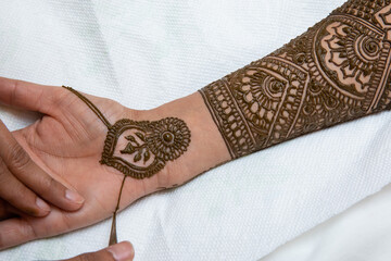 Creating Henna art on the hand of Indian bride