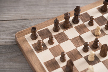 Chess pieces are laid out on a wooden chess board. Close-up of chess pieces top view symbol of wisdom and speed of decisions. Chess strategy, game of chess
