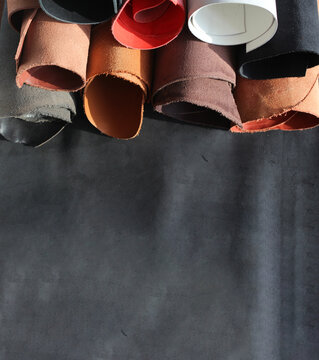 Close-up pieces of the leather material on the working desk in the leather workshop. Vertical banner with spece for text