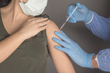 Coronavirus vaccine concept and background. Woman in medical face mask getting Covid-19 vaccine.