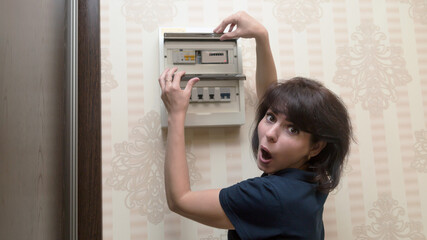 An adult woman looks electric meter readings with horror and surprise. The concept of increasing electricity prices.