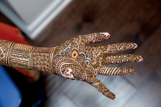 Drawing Henna art on the hand of Indian bride