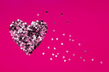Valentine's Day heart made of confetti on a dark pink background. Copy space