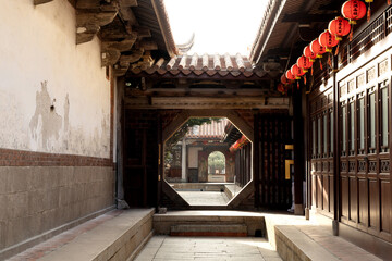 Fototapeta na wymiar Chinese moon gate with a view of Chinese temple, red lanterns under the eaves.