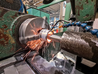 Sparks and coolant scatter in the internal grinding shop at the plant on a CNC machine.