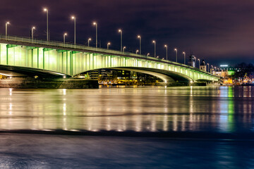 The illuminated Deutz Bridge over the moving river Rhine at Cologne night.