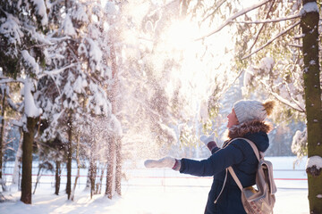 Happy Asian woman walking in winter snow forest. Happy young woman play with snow in sunny winter day, enjoy winter, frosty day. woman throws white, loose snow into the air.