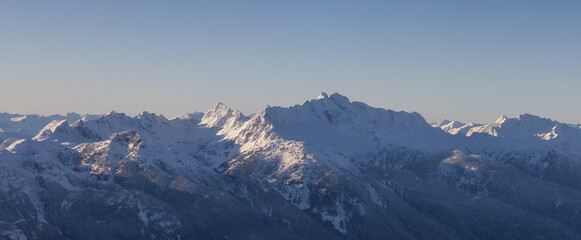 Aerial Panoramic View of Canadian Mountain covered in snow during sunny winter evening. Located near Squamish, North of Vancouver, British Columbia, Canada. Nature Background Panorama