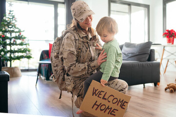Content military woman hugging son with greeting board