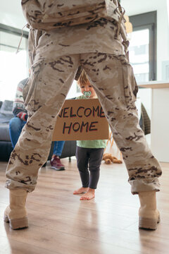 Son greeting faceless military parent with signboard
