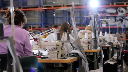 Many seamstresses work in a garment factory. Working process at a garment factory. Large sewing workshop. Seamstresses make products in a factory. Garment factory