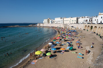 Gallipoli, Puglia, Italy. August 2021. The sandy beach in the old town is packed with people bathing and sunbathing.