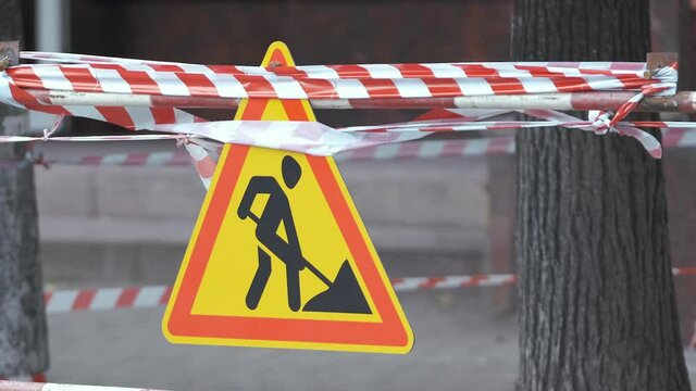 Warning roadworks sign and safety barrier on city street during maintenance repair work