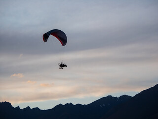 Silhouette powered paraglider against evening sky. Paragliding concept, horizontal photo.