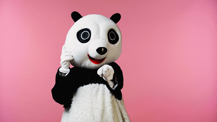 person in panda bear costume pointing with finger at camera isolated on pink.