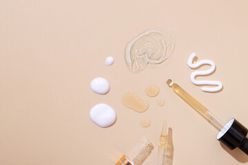 Smears of cream, gel and drops of oil or tincture and a pipette on beige background. Skin care spa concept