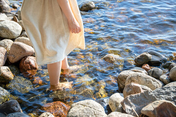 Woman in white dress walking at rocky beach