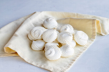 Small white meringues on white fabric. Macro shot. horizontal view