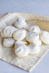 Small white meringues on white fabric. Macro shot. Vertical view