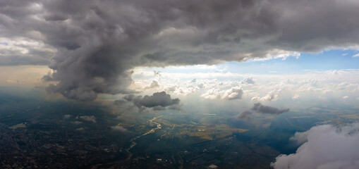 Aerial view from airplane window at high altitude of distant city covered with puffy cumulus clouds...