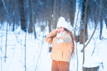 Fototapeta na wymiar Cute little teenage girl having fun playing with snowballs, ready to throw the snowball.