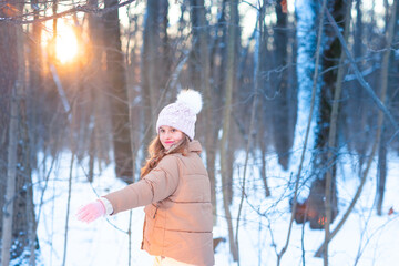 Cute little teenage girl having fun playing with snowballs, ready to throw the snowball.