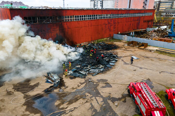 Aerial view of firefighters extinguishing fire in industrial area.