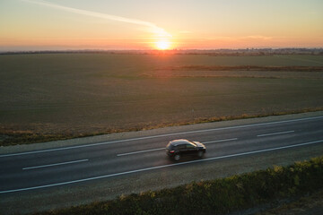 Aerial view of intercity road with blurred fast driving car at sunset. Top view from drone of highway traffic in evening