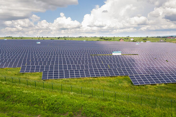 Aerial view of solar power plant on green field. Electric panels for producing clean ecologic energy.