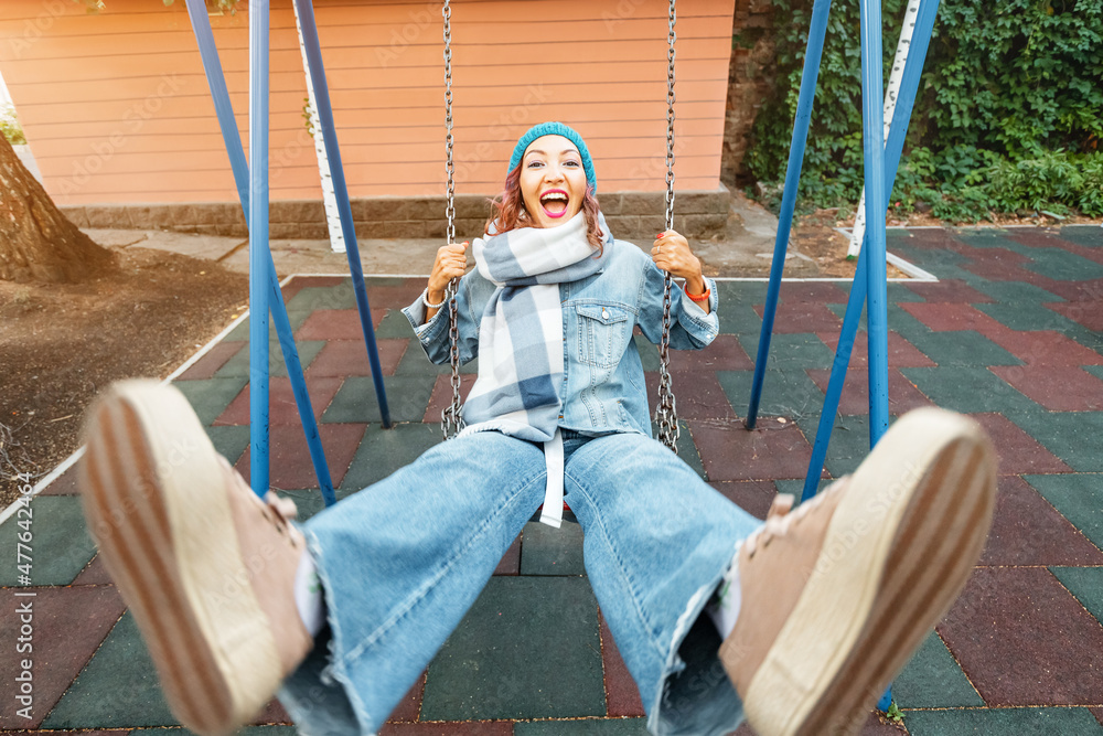 Wall mural infantile and childish happy woman or a teenage girl swings on seesaw. concept of psychology and soc