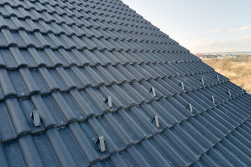 Closeup snow guard for safety in winter on house roof top covered with ceramic shingles. Tiled...