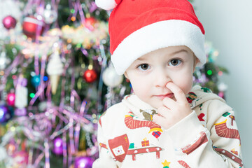 little boy in santa hat digging in a nose