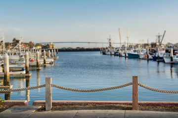 Fototapeta premium Rope railing with the blurred background of fishing boats and Coronado bridge, Tuna Harbor, San Diego bay, California