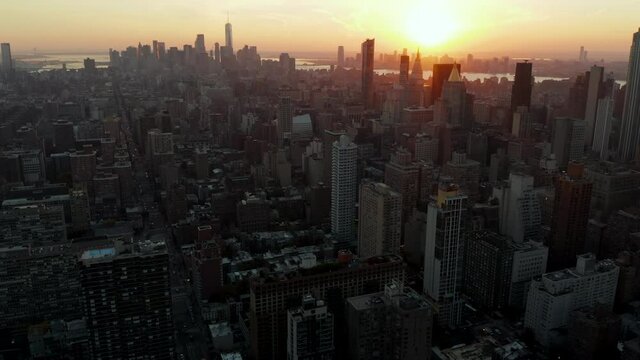 Backwards fly above city. Aerial view of cityscape against golden sunset. Manhattan, New York City, USA