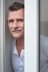 portrait of handsome man in his 50s standing by window