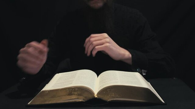 Christian pastor reading the Holy Bible. Hands turning pages