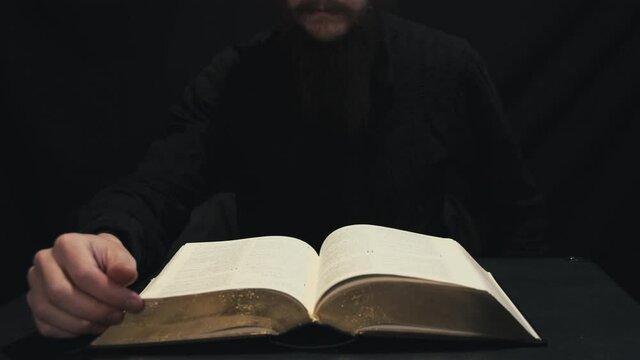 Christian pastor reading the Holy Bible. Hands turning pages