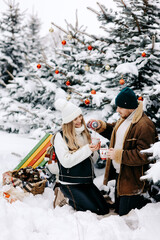 Fototapeta na wymiar couple in winter drinking tea in pine forest, Christmas atmosphere.