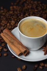 A cup of espresso coffee with cinnamon, coffee beans around. Natural coffee with additives. Invigorating drink