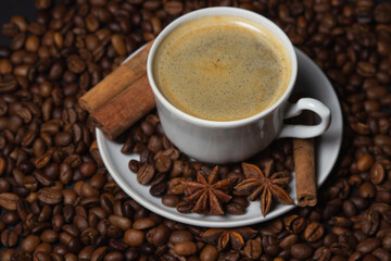 A cup of espresso coffee with cinnamon, coffee beans around. Natural coffee with additives. Invigorating drink