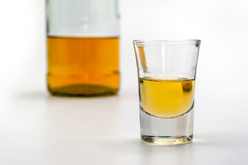 Alcoholic drink in a glass and bottle of brandy in the back on white table. Of strong alcoholic intoxication. The concept of alcohol dependence. Alcohol intoxication.
